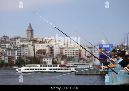 Auf der Galata-Brücke sind Fischer mit ihren Angelruten vor der Aussicht auf Istanbul zu sehen. Selektiver Fokus. Stockfoto