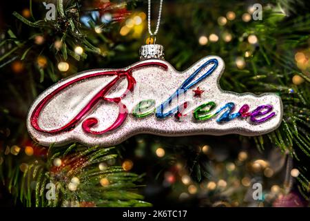 Weihnachtsschmuck, der sagt, glauben an bunte Buchstaben auf einem Hintergrund von goldenen Lichtern. Stockfoto