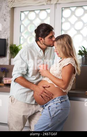 Süßes vertikales Porträt des kaukasischen Schwangeren Paares erwartet Baby zu Hause bequem. Stockfoto