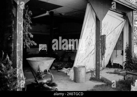 Ein stockender Stand in einer großen Garage mit kaputten Türen und Baumaschinen, die im Cogswell Grant im historischen Essex, Massachusetts, zurückgelassen wurden. T Stockfoto