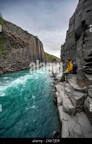 Tourist steht am Fluss im Stuolagil Canyon, türkisblauer Fluss zwischen Basaltsäulen, Egilsstadir, Island Stockfoto