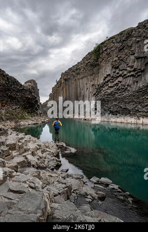 Tourist steht am Fluss im Stuolagil Canyon, türkisblauer Fluss zwischen Basaltsäulen, Egilsstadir, Island Stockfoto