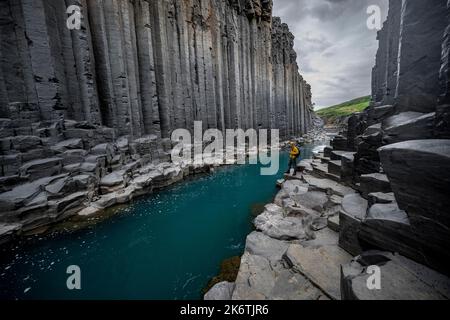 Tourist steht am Fluss im Stuolagil Canyon, türkisblauer Fluss zwischen Basaltsäulen, Egilsstadir, Island Stockfoto