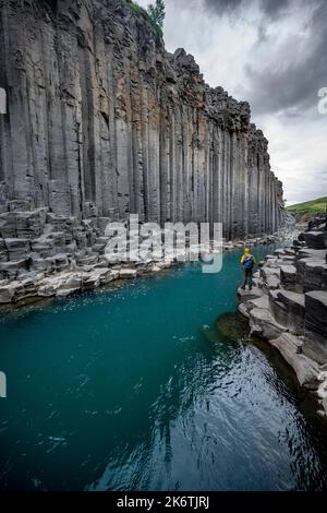 Tourist steht am Fluss im Stuolagil Canyon, türkisblauer Fluss zwischen Basaltsäulen, Egilsstadir, Island Stockfoto