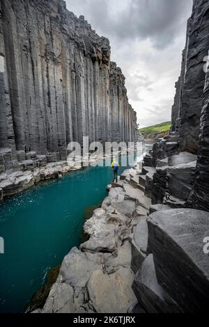 Tourist steht am Fluss im Stuolagil Canyon, türkisblauer Fluss zwischen Basaltsäulen, Egilsstadir, Island Stockfoto