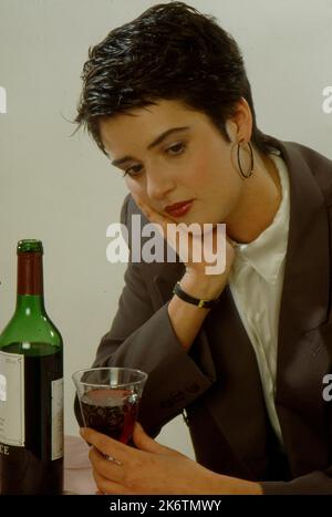 Junge Frau trinkt Rotwein, deprimiert Stockfoto