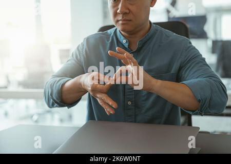 Nahaufnahme eines Geschäftsmannes, der Gebärdensprache verwendet, während er mit dem im Büro sitzenden Kunden spricht Stockfoto