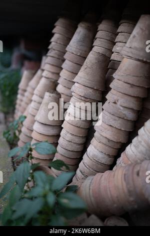 Nahaufnahme von Stapeln alter verwitterter Terrakotta-Blumentöpfe im Gartenschuppen Stockfoto