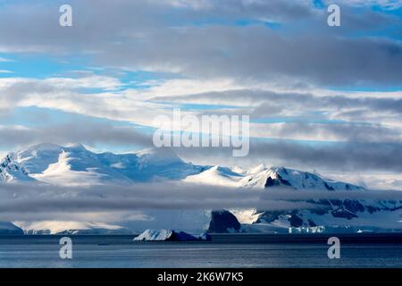 Schnee- und wolkenbedeckte Berge der antarktischen Halbinsel mit dunklen Felsen von Spitzspitze und zeiss-Nadel der halbinsel arctowski. Antarktis Stockfoto