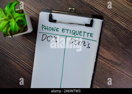 Konzept der Telefon-Etikette Do's und Don't's schreiben auf Papierkram isoliert auf Holztisch. Stockfoto