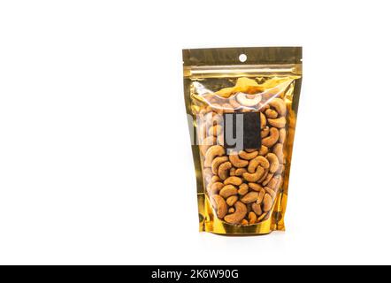 Cashewnüsse in Fensterbeutelverpackung mit Kunststoff, goldfarben verpackt. Vorderansicht mit einem leeren quadratischen schwarzen Etikett für das Markendesign. Das Bild ist eingeschaltet Stockfoto
