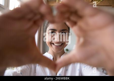 Porträt einer glücklichen indischen Frau verbindet sich mit den Fingern und zeigt das Liebessymbol Stockfoto