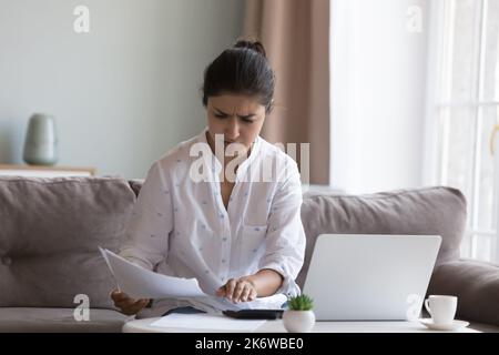 Die verrunzelte indische Frau berechnet die Ausgaben und fühlt sich wegen des Geldmangeles aufgebracht Stockfoto