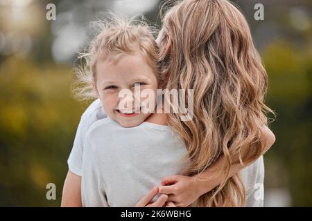 Porträt von entzückenden kleinen Mädchen auf der Schulter ihrer Mutter liegen. Fröhliches kleines Mädchen, das ihrer Mutter Liebe und Zuneigung zeigt, während sie Zeit verbringt Stockfoto