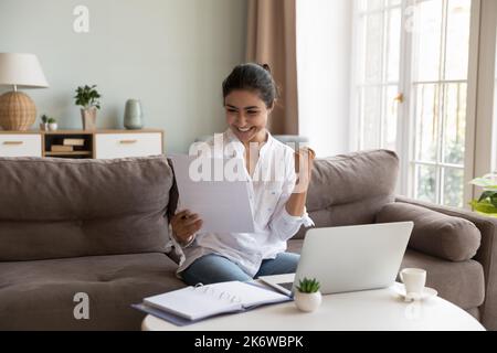 Glückliche indische Frau las gute Nachrichten in Papierbrief Stockfoto