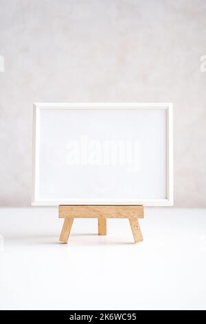 Leerer Bilderrahmen in minimalistischer Inneneinrichtung auf weißem Tisch. Stockfoto