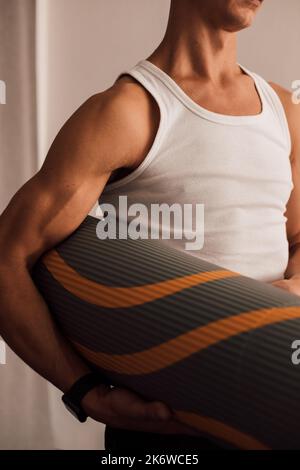 Ein Mann hält eine Yogamatte in den Händen Stockfoto