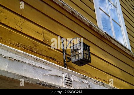 Alte, helle Laterne, die an einer hölzernen Gebäudewand in Porvoo, Finnland, hängt Stockfoto