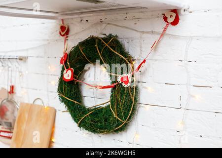 Dekorativer Weihnachtskranz an der Tür mit Zweigen. Dekoration an den Haustüren im neuen Jahr Stockfoto