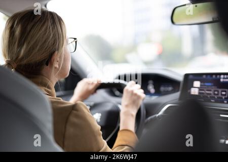 Geschäftsfrau, die ein Auto zur Arbeit fährt. Weibliche Lenkerin auf der Straße Stockfoto