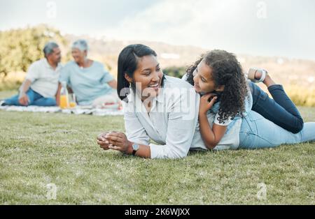 Die Dinge, die wichtig sind, sind Glaube, Familie und Freunde. Eine Mutter und Tochter liegen auf dem Gras in einem Park. Stockfoto