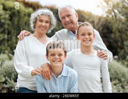 Sind sie nicht lieblich. Zwei Geschwister posieren für ein Bild mit ihren Großeltern draußen. Stockfoto