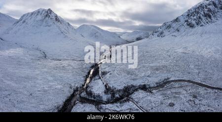 Atemberaubende Luftdrohnen-Landschaftsaufnahme von Stob Dearg und Glencoe in den schottischen Highlands bei tiefem Schneefall und schönem blauen Himmel Stockfoto