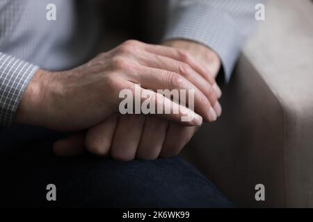 Nahaufnahme, Handflächen eines unbekannten älteren Mannes auf den Knien gefaltet Stockfoto