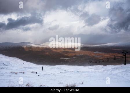 Wunderschöne Winterlandschaft von der Bergspitze in den schottischen Highlands hinunter in Richtung Rannoch Moor während Schneesturm und Spindrift von der Bergspitze hinein Stockfoto