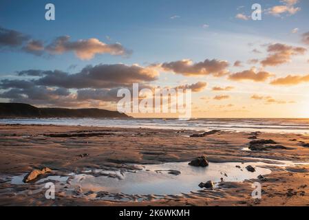 Schönes Landschaftsbild im Sommer bei Sonnenuntergang von Widemouth Bay in Devon England mit goldenem Stundenlicht am Strand Stockfoto