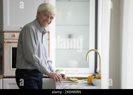 Hoary reifen Single man schneiden Avocado für gesunde Ernährung Salat Stockfoto