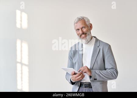 Lächelnder alter leitender Geschäftsmann, der ein Tablet auf weißem Hintergrund verwendet. Stockfoto