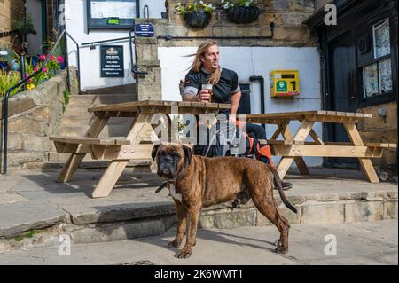 Ein Besucher von Robin Hoods Bay, der ein Bier vor einem öffentlichen Haus in North Yorkshire, Großbritannien, genießt Stockfoto