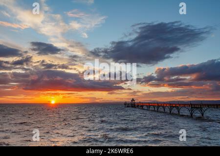 Clevedon Pier, wo die Sonne über den walisischen Hügeln untergehen wird Stockfoto