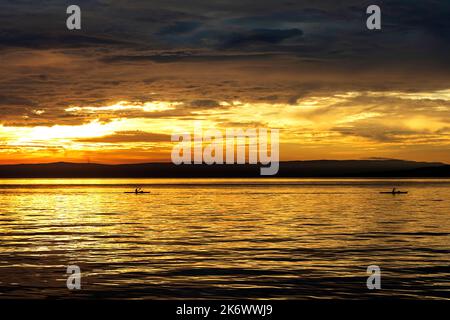 Zwei Seekajakare, die bei Sonnenuntergang in der Nähe des alten baska-Dorfes nahe punat auf der Insel krk in kroatien paddeln, Stockfoto