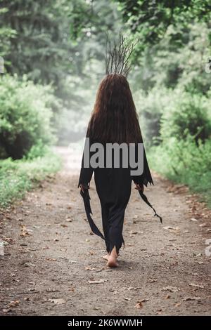 Eine kleine schöne Waldfee in einer Krone aus Ästen, Halloween-Konzept Stockfoto