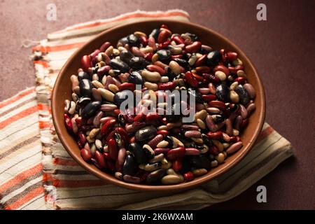 Bunte Bio-Bohnen auf burgunderrotem Hintergrund Stockfoto