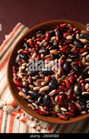 Bunte Bio-Bohnen auf burgunderrotem Hintergrund Stockfoto