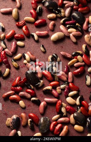 Bunte Bio-Bohnen auf burgunderrotem Hintergrund Stockfoto