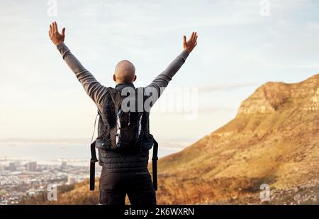 Der Blick von oben. Rückansicht eines nicht erkennbaren jungen Mannes, der die Aussicht während seiner Wanderung in den Bergen genießt. Stockfoto