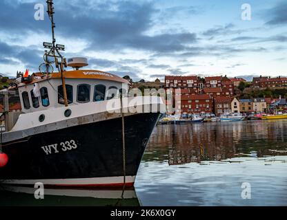 Ein kleines Fischerboot, das in Whitby anlegt, legt nach einem Tag Angeln in der Dämmerung an Stockfoto