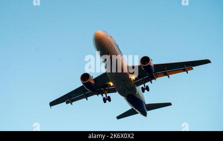 Die Silhouette eines Passagierflugzeugs, das vor dem Hintergrund des Sonnenuntergangs landet. Stockfoto
