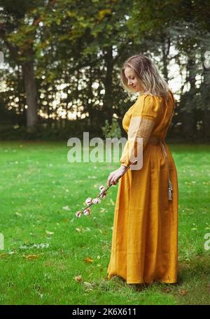 Schöne ukrainische Frau in besticktem Kleid hält einen Zweig aus Baumwolle Stockfoto