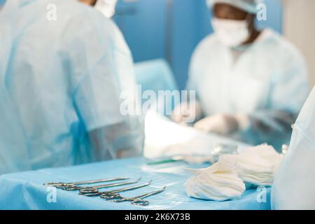 Werkzeuge für die Operation im Vordergrund und ein Team Von Chirurgen im Hintergrund, die die Operation durchführen Stockfoto