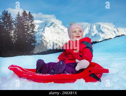 Glückliches kleines Mädchen geht im Schlitten bergab Stockfoto