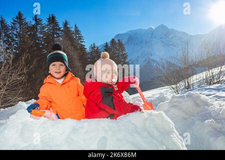 Zwei Kinder, Junge mit Schwester Mädchen spielen in Schnee Festung draußen Stockfoto