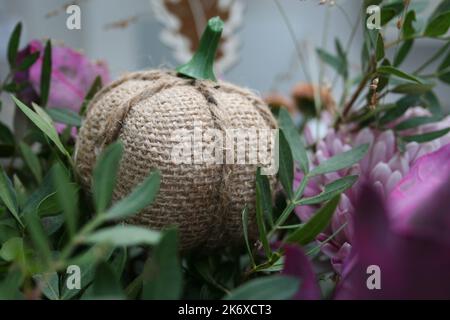 Nahaufnahme eines gestrickten Kürbisses in Blumen. Stockfoto