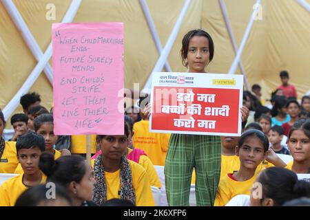 Die Menschen in der Gemeinschaft des Sanjay Camps halten Plakate während der ‘kinderheiratsfreien Indien-Kampagne“, die eine NGO am Sonntag, 16. Oktober 2022, im Slum des Sanjay Camps in Neu-Delhi in Indien veranstaltet hat. Mehr als 500 Kinder und Gemeindefrauen versammelten sich, um der Kampagne beizuwohnen. Indien beobachtet Kindermädchenehen vor dem gesetzlichen Alter aufgrund mangelnder Alphabetisierung unter den Menschen, die in Dörfern und Slums leben. Foto von Anshuman Akash/ABACAPRESS.COM Quelle: Abaca Press/Alamy Live News Stockfoto