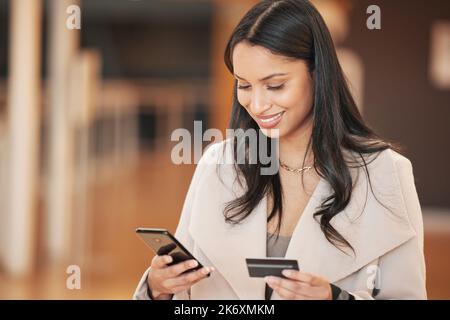 Sie müssen nie eine andere Rechnung verpassen. Eine junge Frau, die ihr Smartphone benutzt, um eine Online-Zahlung mit ihrer Kreditkarte zu tätigen. Stockfoto