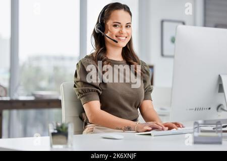 Lasst mich sehen, was ich tun kann. Kurzportrait einer attraktiven jungen Callcenter-Agentin, die an ihrem Schreibtisch im Büro arbeitet. Stockfoto